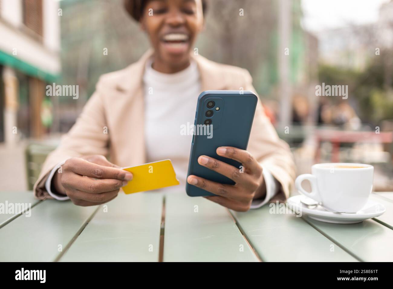 Une femme noire savoure une journée en plein air dans un cadre urbain, tenant un smartphone et une carte la scène présente une table avec un café, mettant en valeur une vibr Banque D'Images