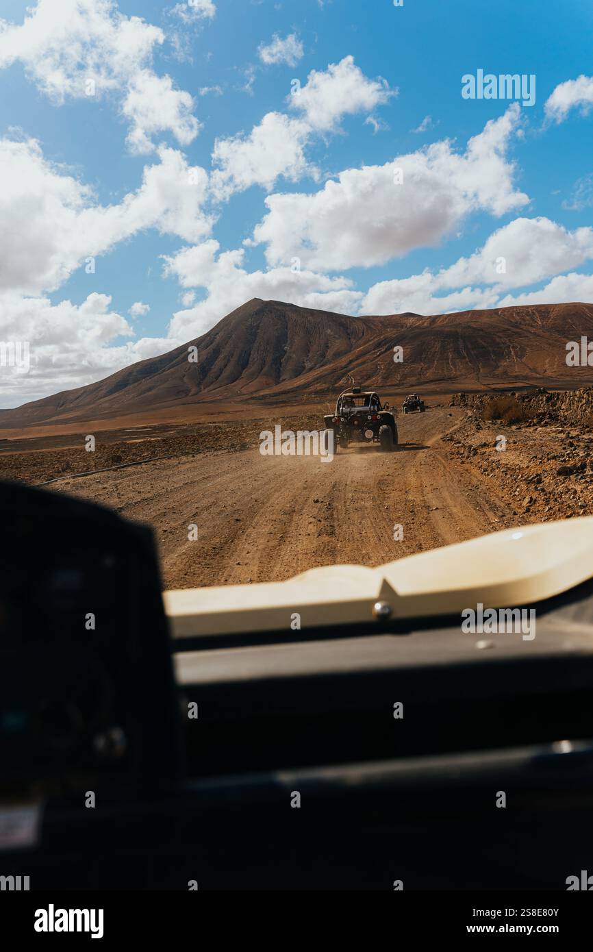 Terrain accidenté de Lanzarote depuis un buggy. De vastes paysages volcaniques, des nuages épars et une route panoramique capturent l'essence de l'aventure et de l'être naturel Banque D'Images