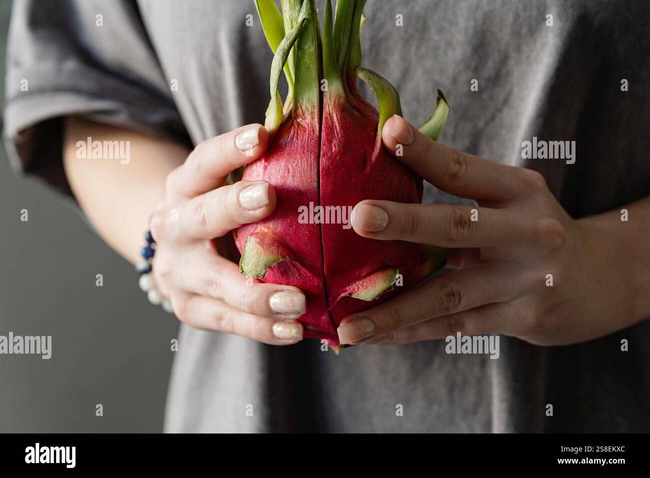 Gros plan de mains féminines tenant un fruit pitahaya vibrant. Banque D'Images