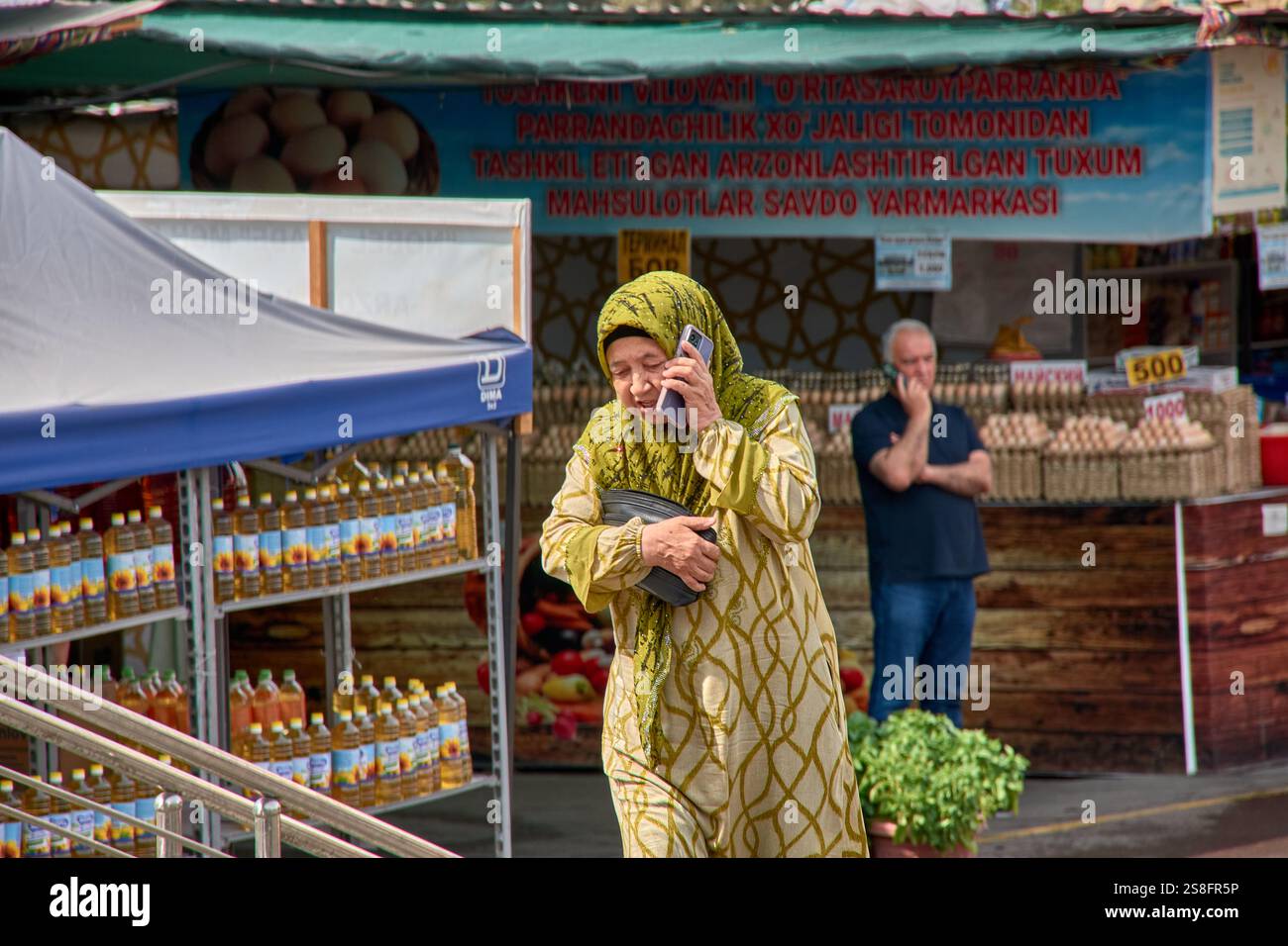 Tachkent, Ouzbékistan;septembre,16,2024:femme musulmane âgée portant un hijab jaune et des vêtements traditionnels alors qu'elle parle sur son téléphone Banque D'Images