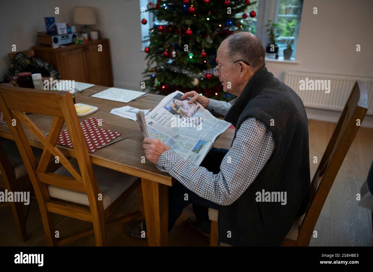 Homme âgé lisant un journal national britannique pendant la période de Noël, Londres, Angleterre, Royaume-Uni Banque D'Images