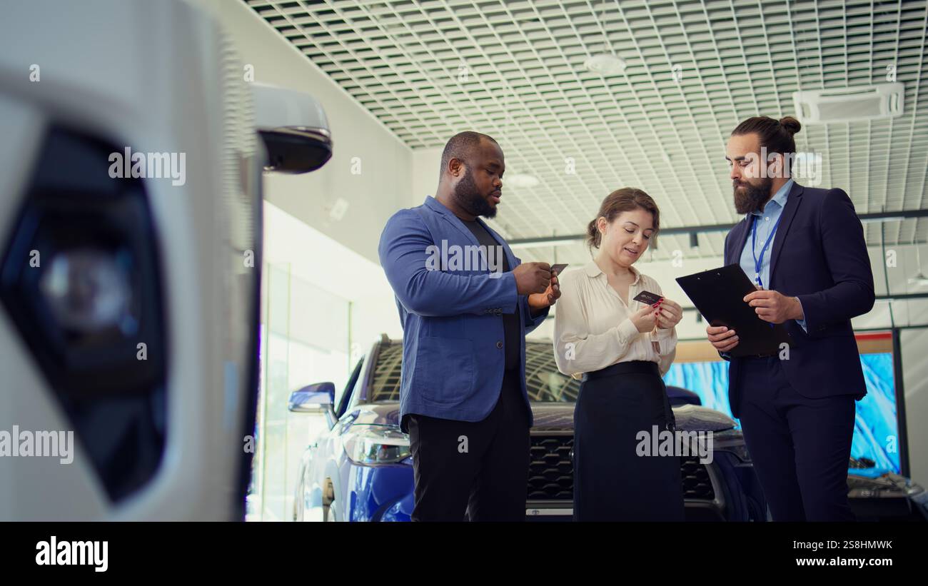 Vendeur de concession automobile offrant des cartes de visite aux clients après avoir négocié les prix des véhicules, en attendant la réponse finale. Agent donnant des cartes de visite aux clients, attendant leur appel, caméra B. Banque D'Images