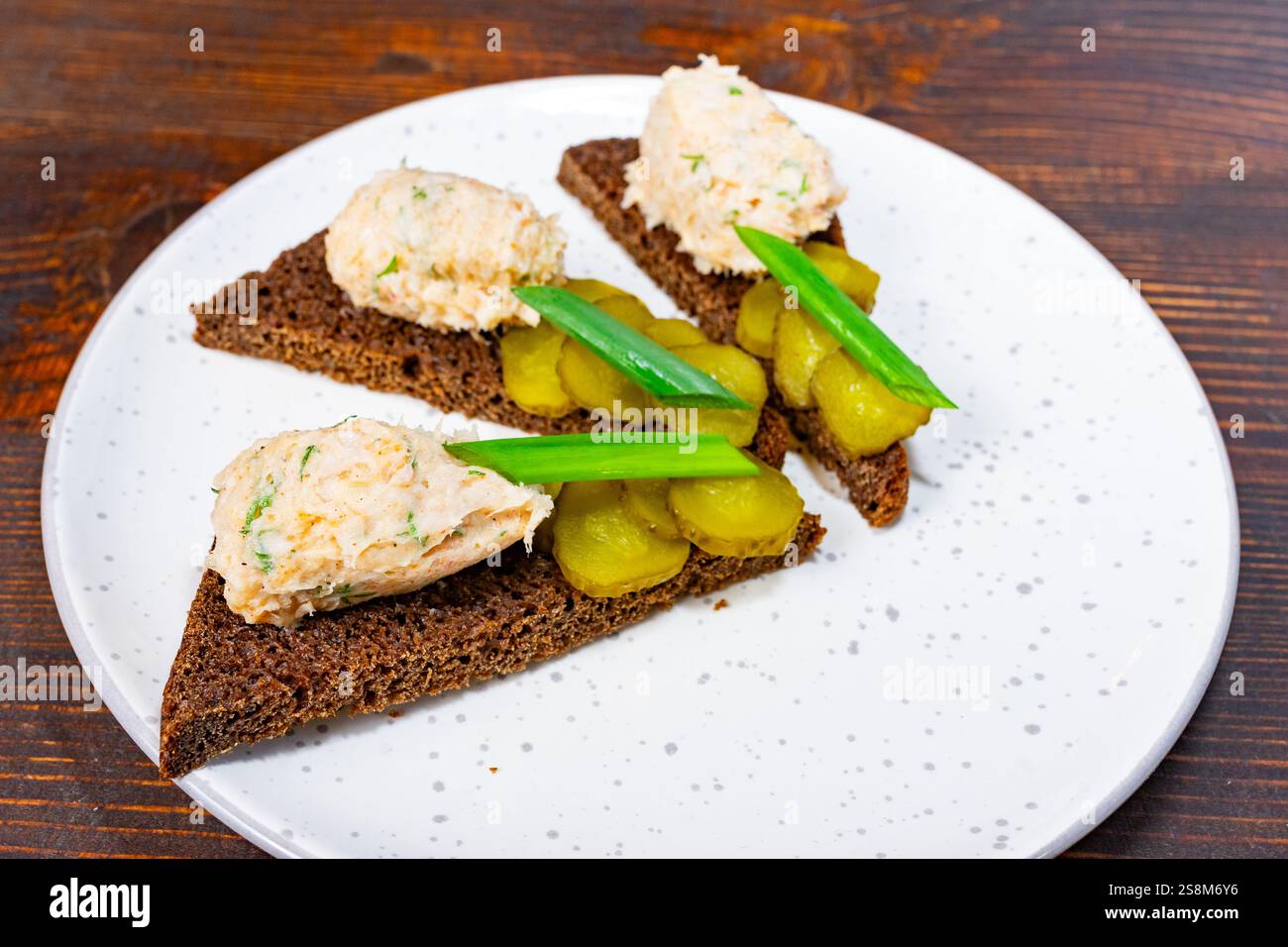 Délicieux canapés faits de pain de seigle foncé surmonté de viande hachée savoureuse et garni de cornichons et d'oignons verts, parfaits pour un elegan Banque D'Images