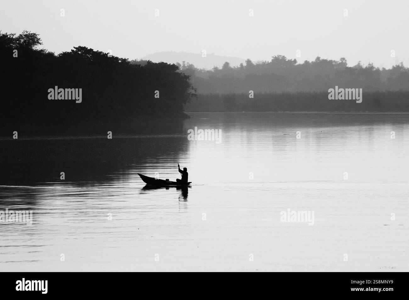Un batelier solitaire avançant à travers les eaux calmes du barrage de Durgapur DVC, au bengale occidental, en Inde. La scène tranquille reflète la sérénité et la solitude Banque D'Images