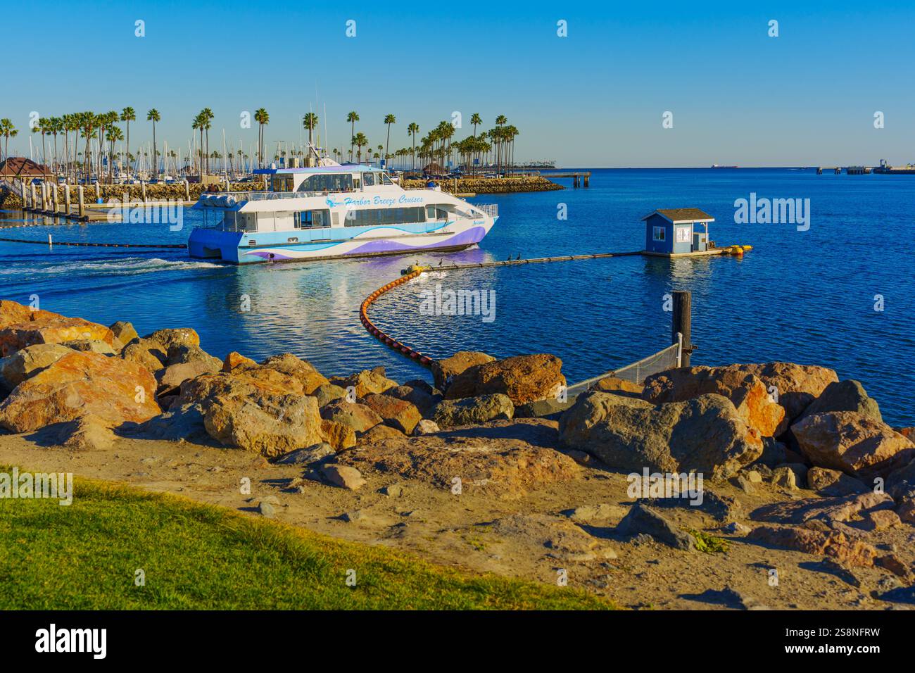 Long Beach, Californie - 15 janvier 2025 : bateau de croisière Harbor Breeze naviguant dans une maison flottante à long Beach, entouré d'eaux calmes et de palmiers Banque D'Images