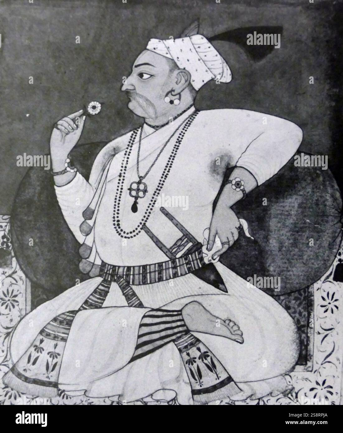 Portrait du rajah Sangram Pal de Basohli (1635-1673) assis en tailleur sur un tapis bleu et blanc ; il allongé contre une rose soutenir tout en examinant une fleur dans sa main droite, et est vêtue d'un blanc jama. En date du 18e siècle Banque D'Images