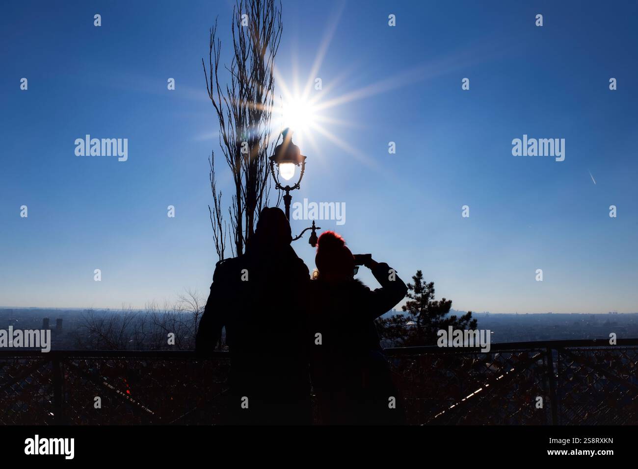 Paris, France, 01.13.2025 Une silhouette d'un couple surplombant Paris par une journée ensoleillée d'hiver. Ciel bleu et rafale de soleil. Banque D'Images