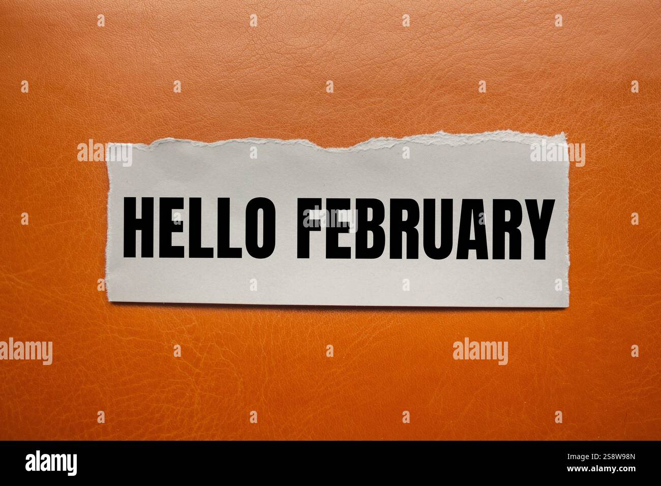 Bonjour février message écrit sur un morceau de papier déchiré déchiré avec fond brun. Symbole conceptuel bonjour février. Copier l'espace. Banque D'Images