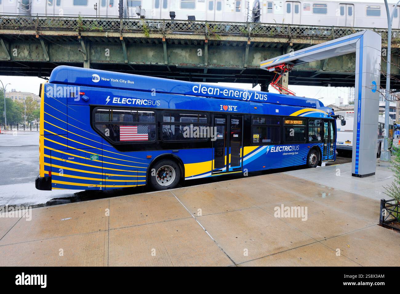 Un bus MTA New York City Electric se recharge à une station de charge pantogragh aérienne à Brooklyn. Le modèle de bus est une charge New Flyer Xcelsior. Banque D'Images