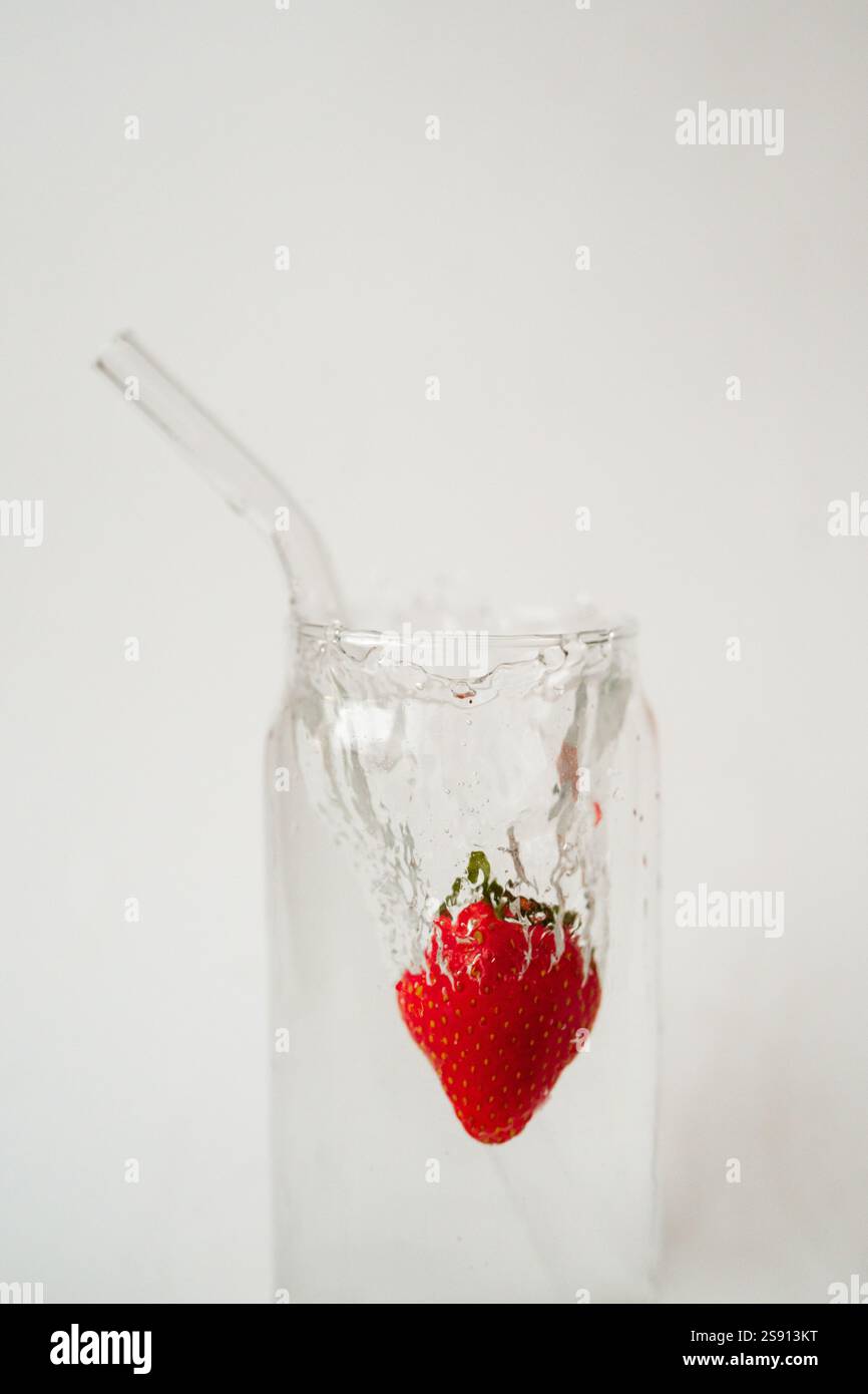 Fraise fraîche éclaboussant dans l'eau dans un verre avec un réutilisable Banque D'Images