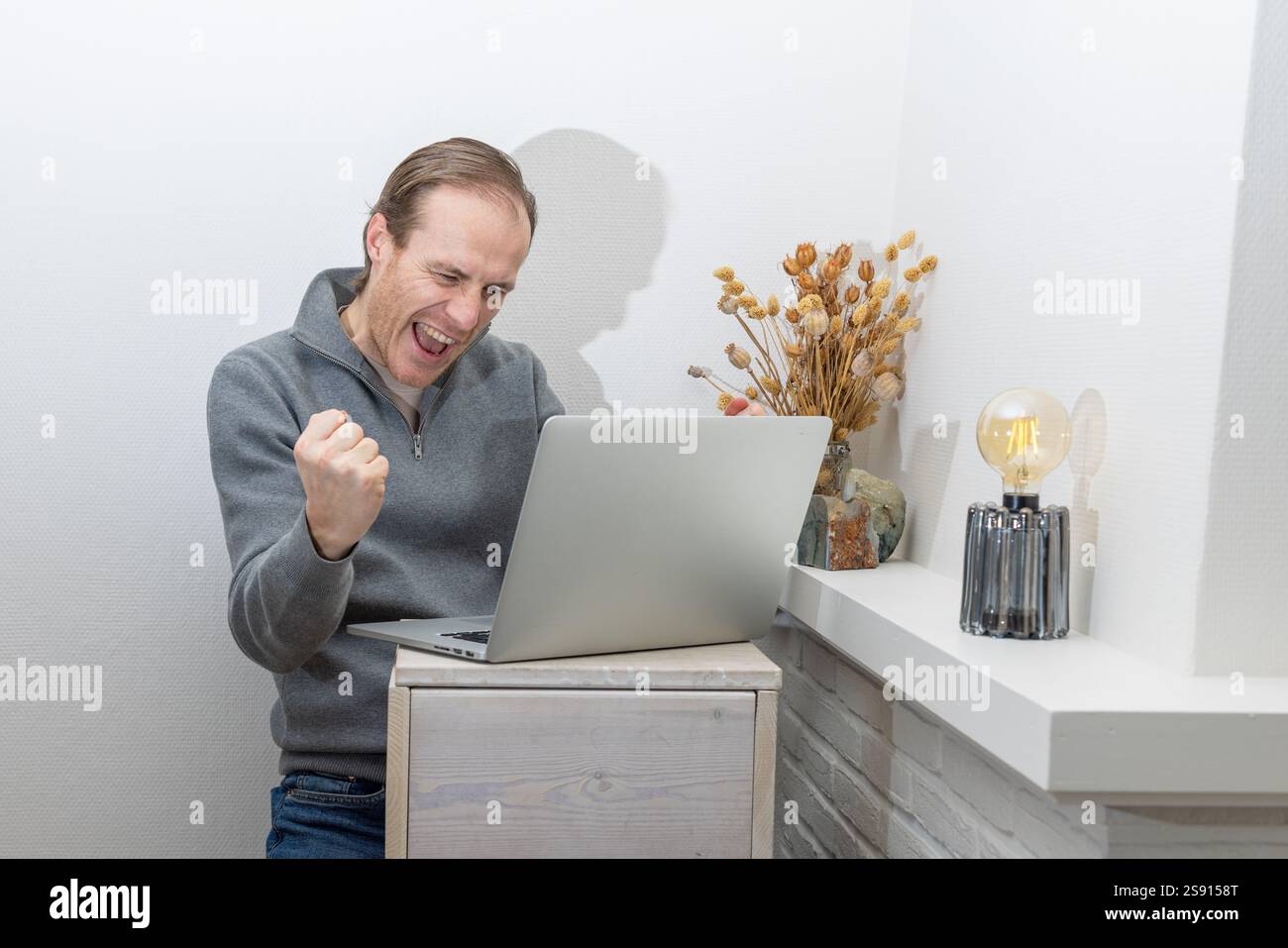 Professionnel enthousiaste célébrant le succès tout en travaillant sur un ordinateur portable Banque D'Images