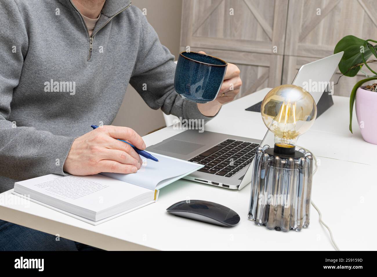 homme d'affaires tenant sa tasse de café tout en lisant dans son livre Banque D'Images