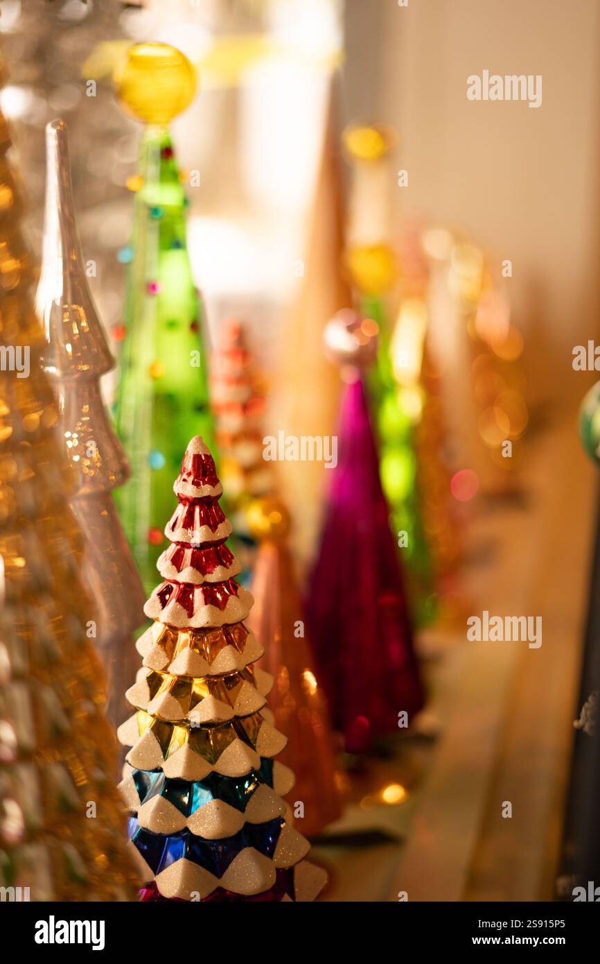 Gros plan d'arbres de Noël en verre colorés avec un éclairage festif chaleureux Banque D'Images