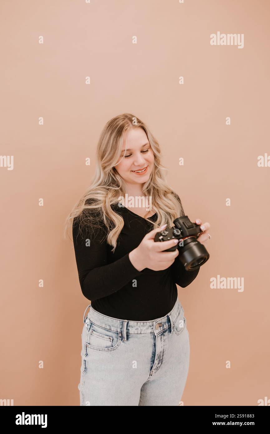 Photographe femme souriante tenant un appareil photo dans le studio Banque D'Images