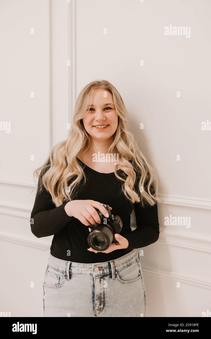 Photographe féminine souriante tenant la caméra sur un fond blanc Banque D'Images