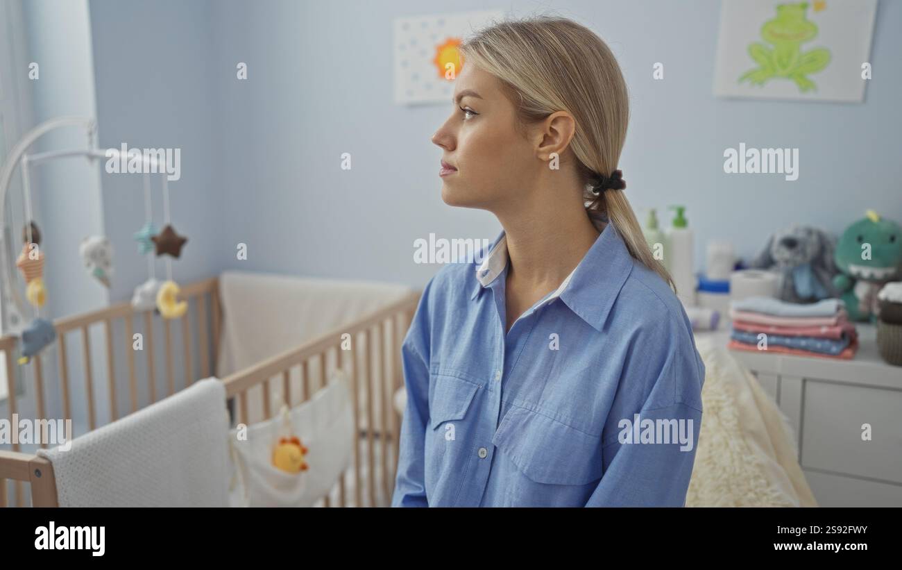 Femme assise dans une chambre à coucher à côté d'un berceau de bébé, avec une expression paisible, dans un cadre de maison confortable. Banque D'Images