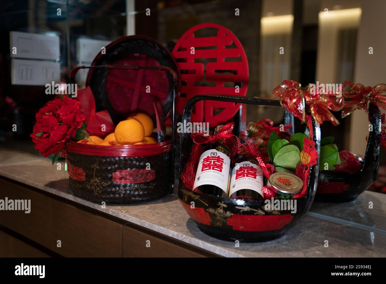 Paniers contenant des cadeaux de mariage (bouteilles, oranges et décorations rouges). Banque D'Images