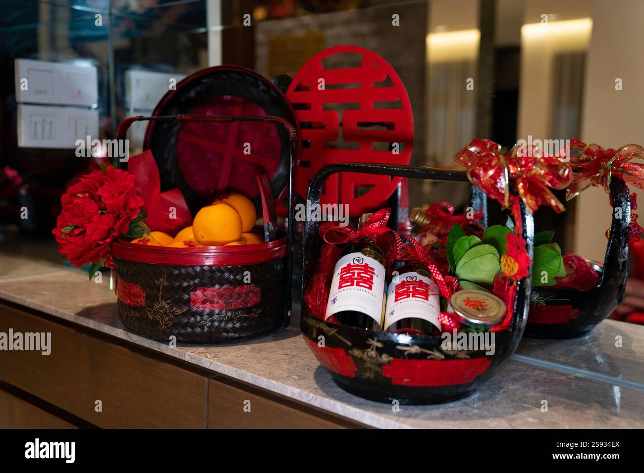 Paniers contenant des cadeaux de mariage (bouteilles, oranges et décorations rouges). Banque D'Images