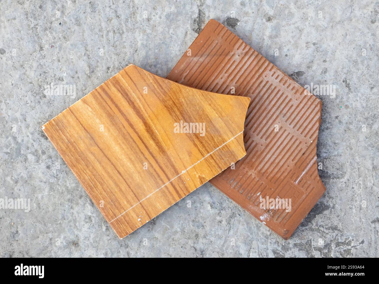 Morceaux cassés de carreaux de céramique texturés en bois sur la surface de béton. Vue de dessus. Banque D'Images