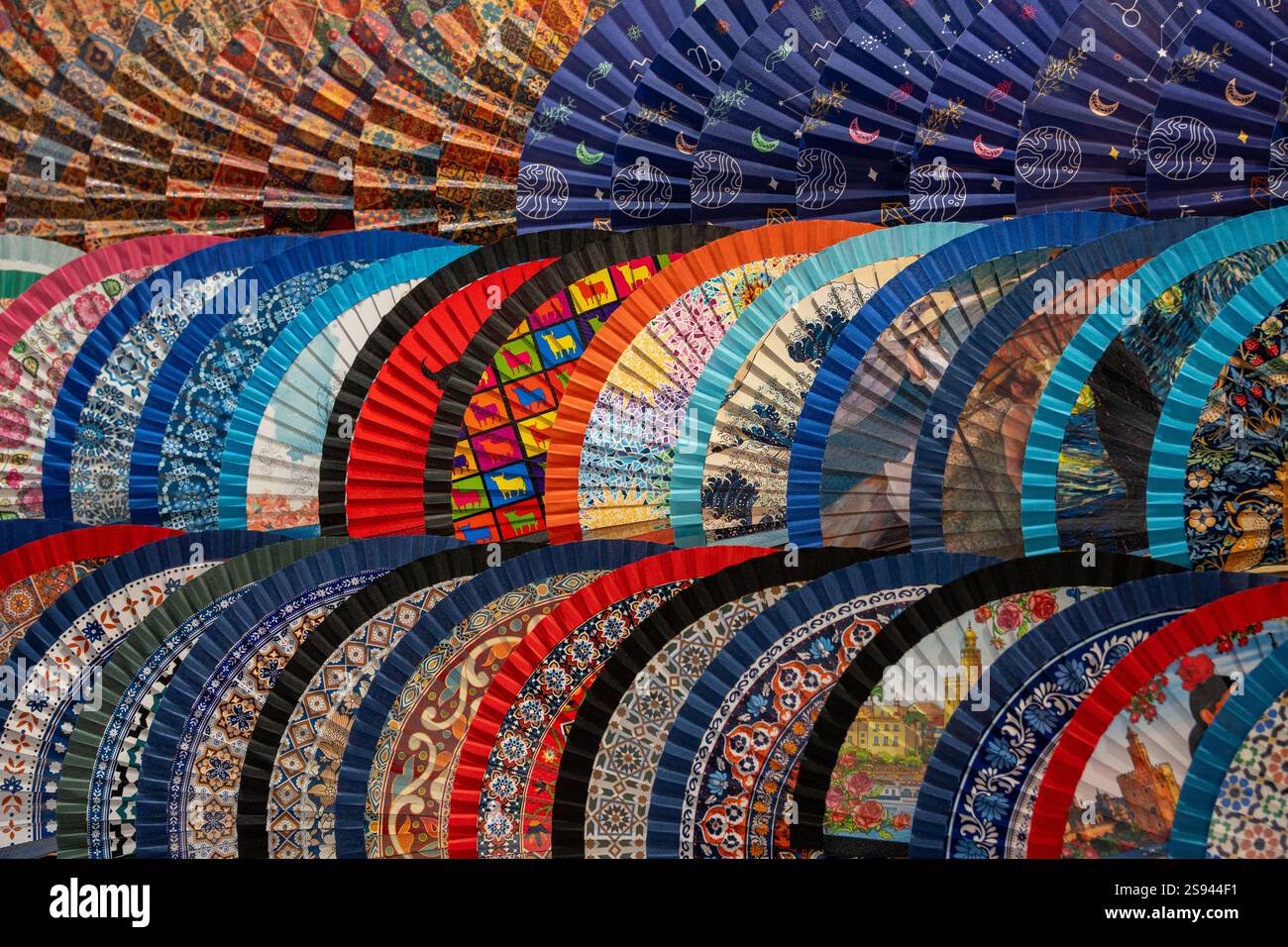 Une collection vibrante de fans espagnols traditionnels avec des motifs colorés et des motifs complexes exposés dans un marché de Séville, en Espagne. Parfait pour sh Banque D'Images