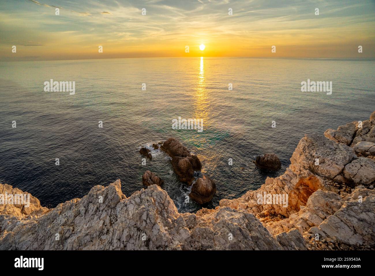 Coucher de soleil sur la mer calme et la côte rocheuse Banque D'Images