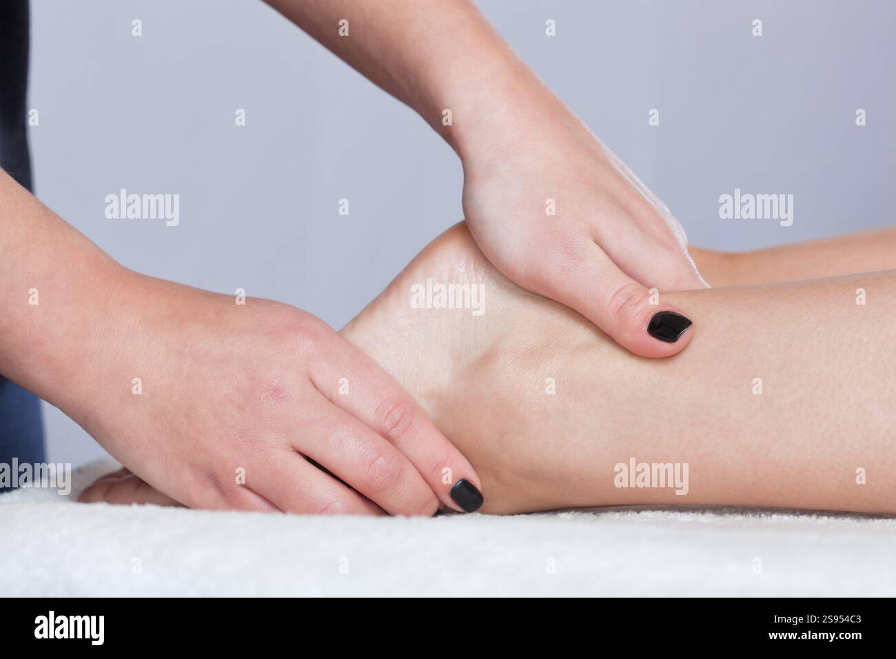 Un médecin orthopédique fait massage du pied et de la jambe inférieure du patient après une blessure entorse à la cheville à la clinique. Cosmétologie et massage concp Banque D'Images