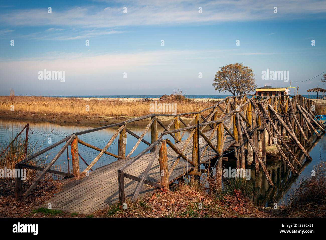 Paysage serein présentant des reflets naturels, avec pont en bois rustique et petit bateau de pêche sur l'eau calme près de la plage de Velika, à Agia, Grèce. Banque D'Images