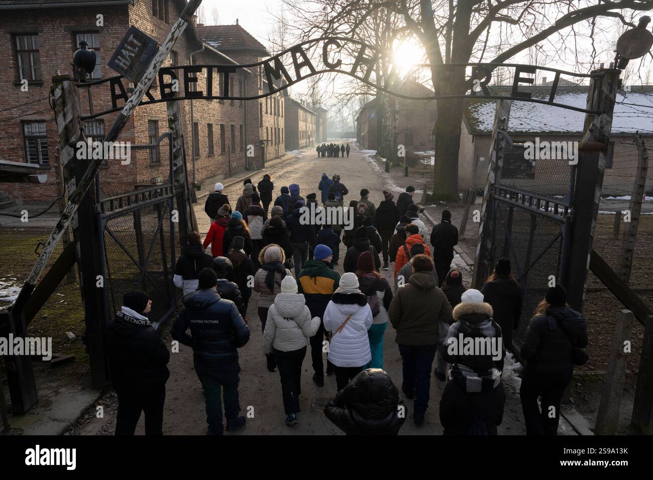 Visitors walk through the ''Arbeit Macht Frei" (Work Sets You Free) gate at the Memorial and Museum Auschwitz-Birkenau, a former Nazi German concentration and extermination camp, in Oswiecim, Poland, Saturday, Jan. 25. 2025. (AP Photo/Oded Balilty) Banque D'Images