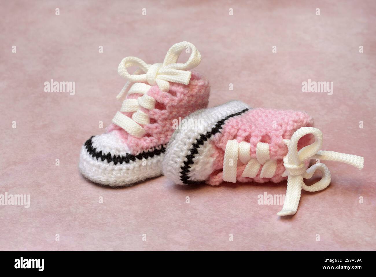 Chaussures de bébé avec fond rose, fait à la main Banque D'Images