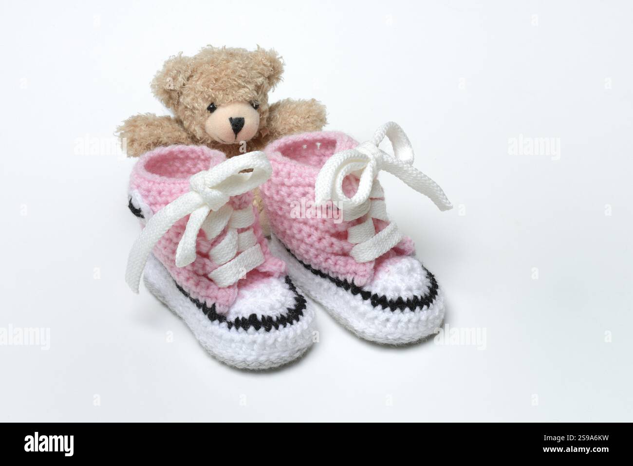 Chaussures de bébé et ours en peluche, fond blanc Banque D'Images