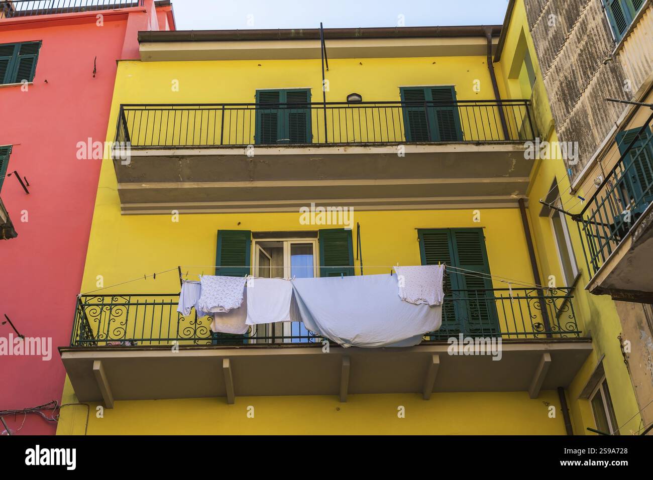 Façade jaune d'immeuble résidentiel avec vêtements lavés et draps de lit bleu séchant sur corde à linge à Riomaggiore, Cinque Terre, la Spezia prov Banque D'Images