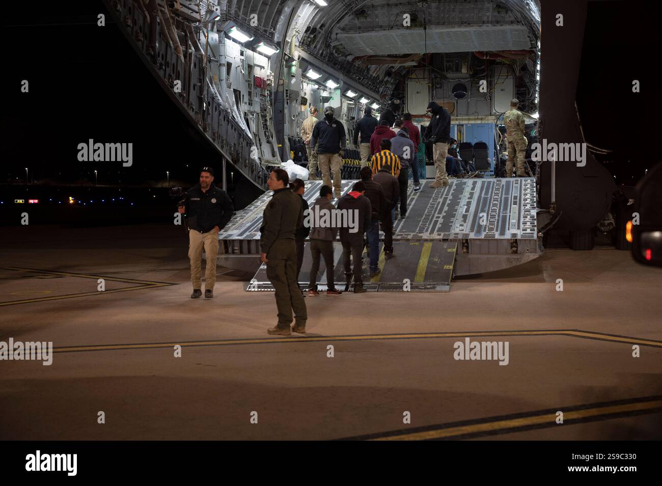 Tucson, États-Unis. 23 janvier 2025. Les agents des douanes et de la protection des frontières des États-Unis guident les migrants sans papiers vers un U. S Air Force avion de transport C-17 Globemaster III pour le premier vol de retrait à l'aéroport international de Tucson, le 23 janvier 2025 à Tucson, Arizona. Les vols de renvoi étaient à la direction du président Donald Trump et c’est la première fois que des avions militaires ont été utilisés pour des vols de déportation. Crédit : TSgt Kimberly Nagle/U. S Air Force/Alamy Live News Banque D'Images