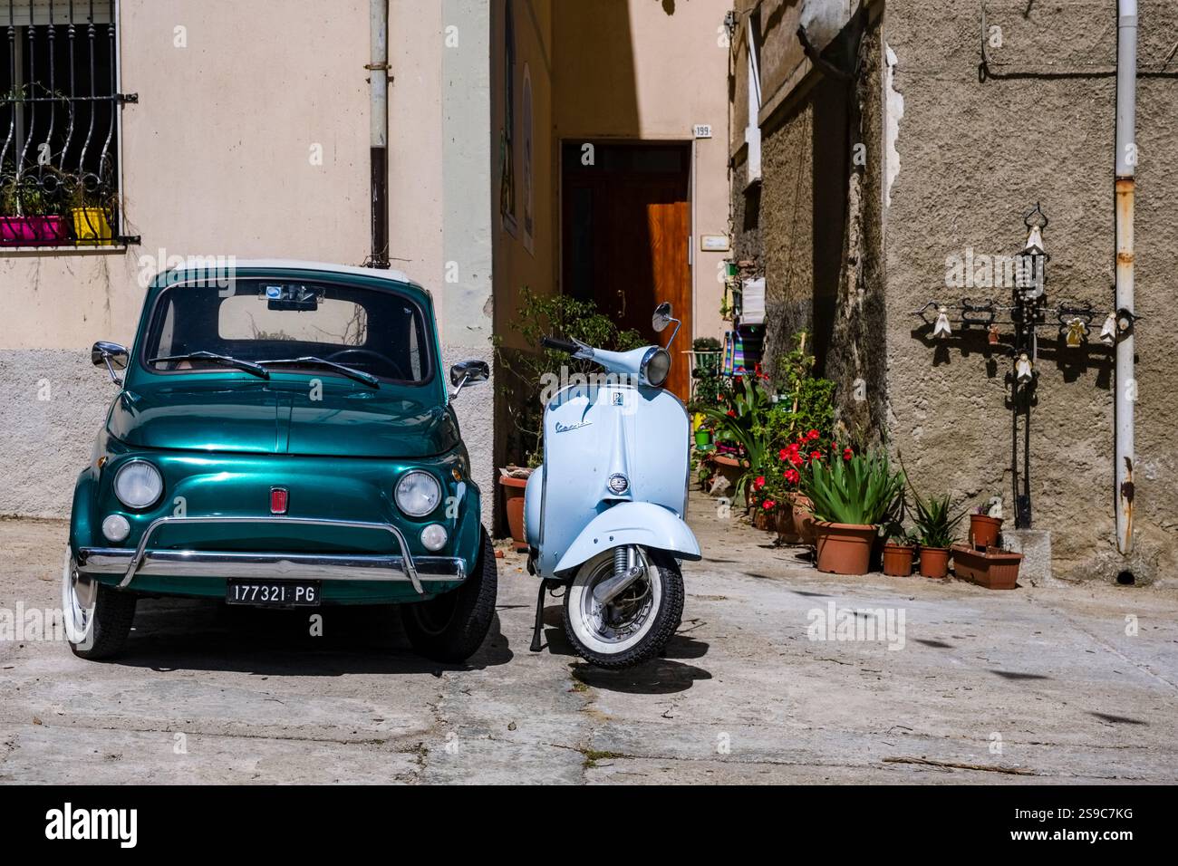 Deux véhicules historiques, une Fiat 500 vert foncé et un scooter Vespa bleu clair, sont garés dans une rue de la petite ville de Bitti. Banque D'Images
