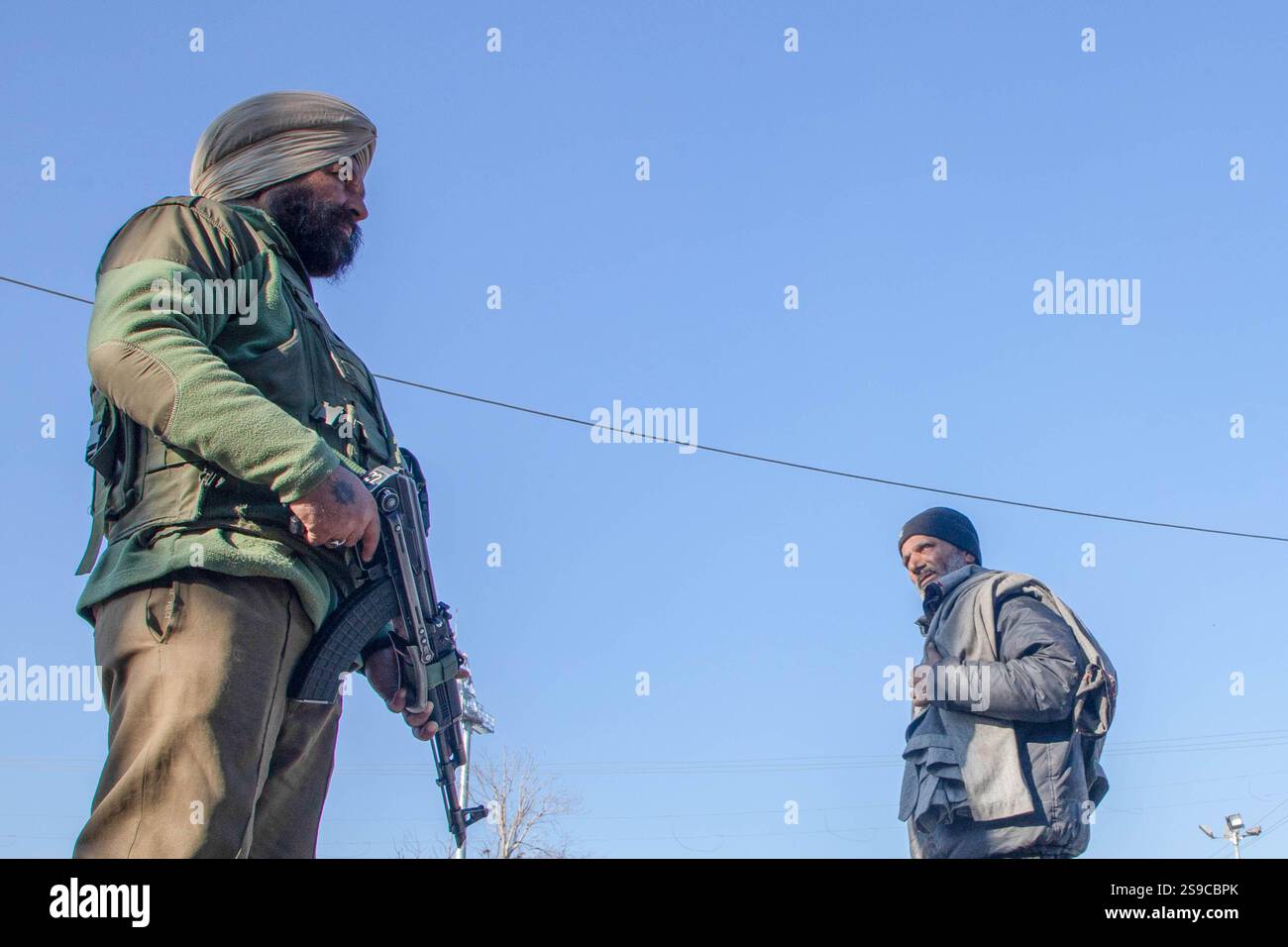 Un homme cachemirien regarde devant un soldat paramilitaire indien qui veille près du lieu principal des célébrations de la fête de la République indienne à Srinagar. La sécurité a été renforcée dans toute la région hostile de l'Himalaya à l'approche de la 76e Journée de la République de l'Inde, prévue le 26 janvier 2025, pour commémorer l'adoption de la Constitution indienne en 1950. (Photo de Faisal Bashir / SOPA images/SIPA USA) Banque D'Images