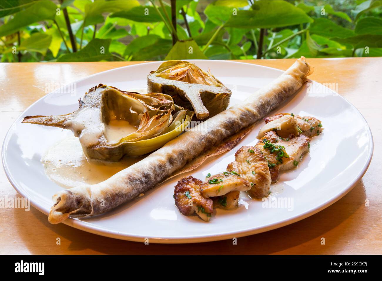 Assiette gastronomique avec artichauts et champignons sur une table Banque D'Images