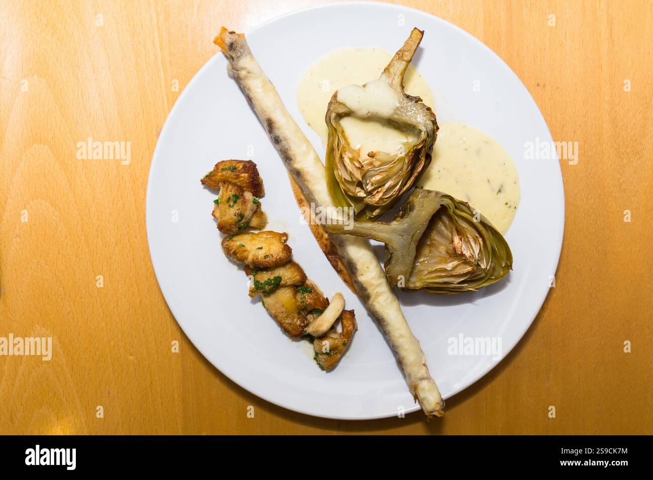 Assiette gastronomique avec artichauts et champignons sur une table Banque D'Images