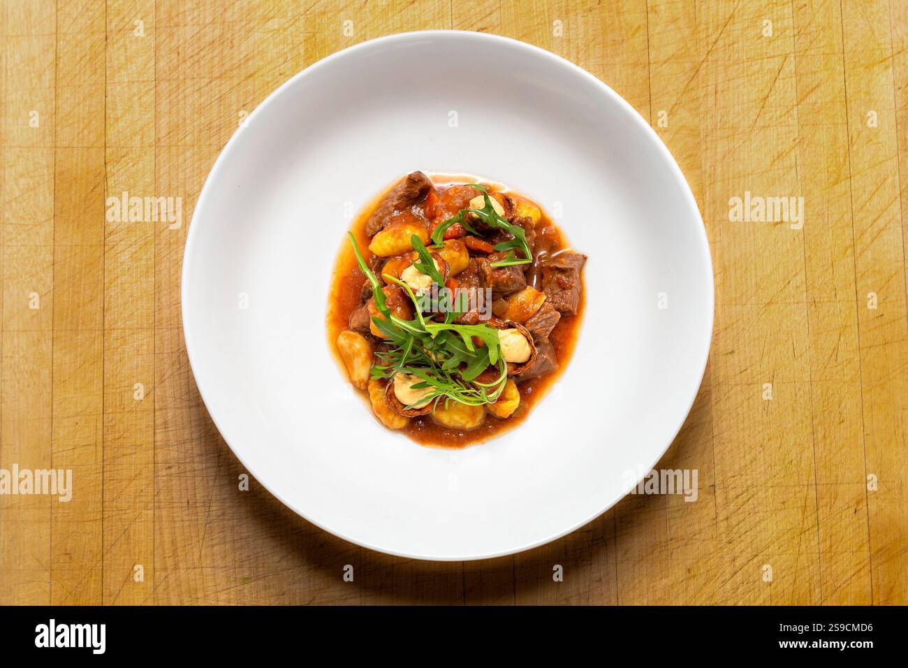 Plat gourmet Gnocchi avec boeuf, tomates et garniture aux herbes fraîches sur la surface du bois, Lark de brouillard Banque D'Images Plat gourmet Gnocchi avec boeuf, tomates et garniture aux herbes fraîches sur la surface du bois, Lark de brouillard Banque D'Images