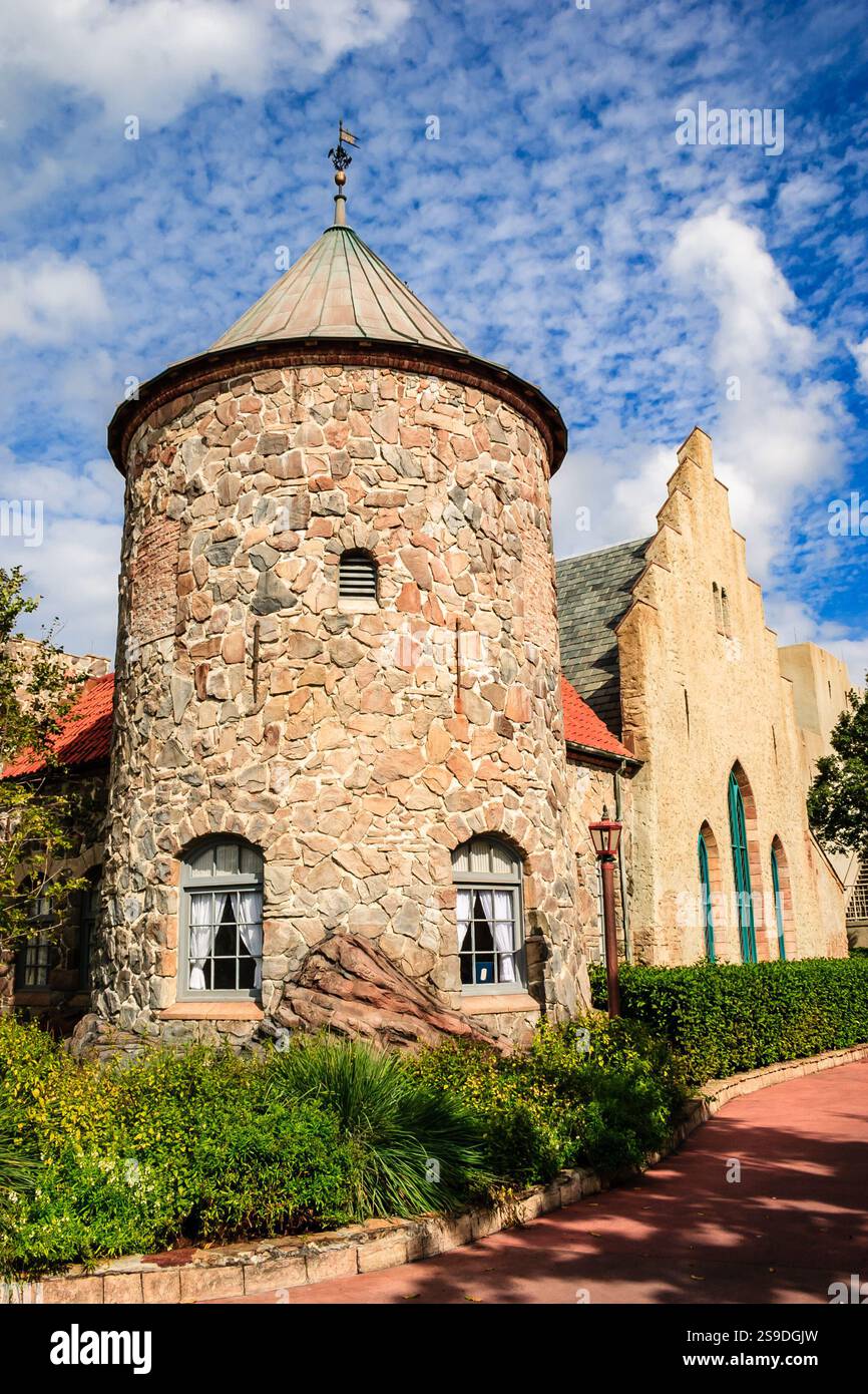 Un bâtiment en pierre avec un clocher et une horloge sur la tour. Le bâtiment a une façade en pierre et un toit en pierre. Le bâtiment est entouré d'un jardin et Banque D'Images