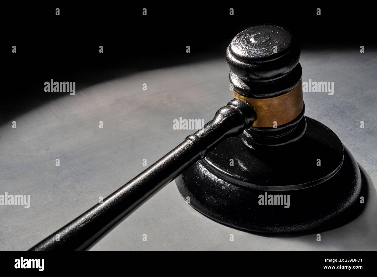 Un marteau sur une surface éclairée par une seule source de lumière, projetant une ombre dramatique. Justice et concept de droit. Banque D'Images