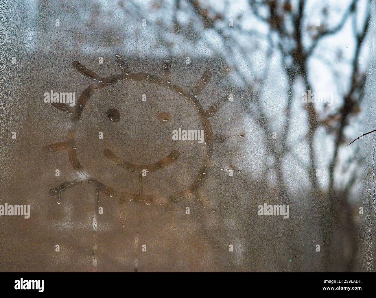 Peint un soleil souriant sur une fenêtre mouillée. le fond est fait de verre humide. concept de bonne humeur Banque D'Images