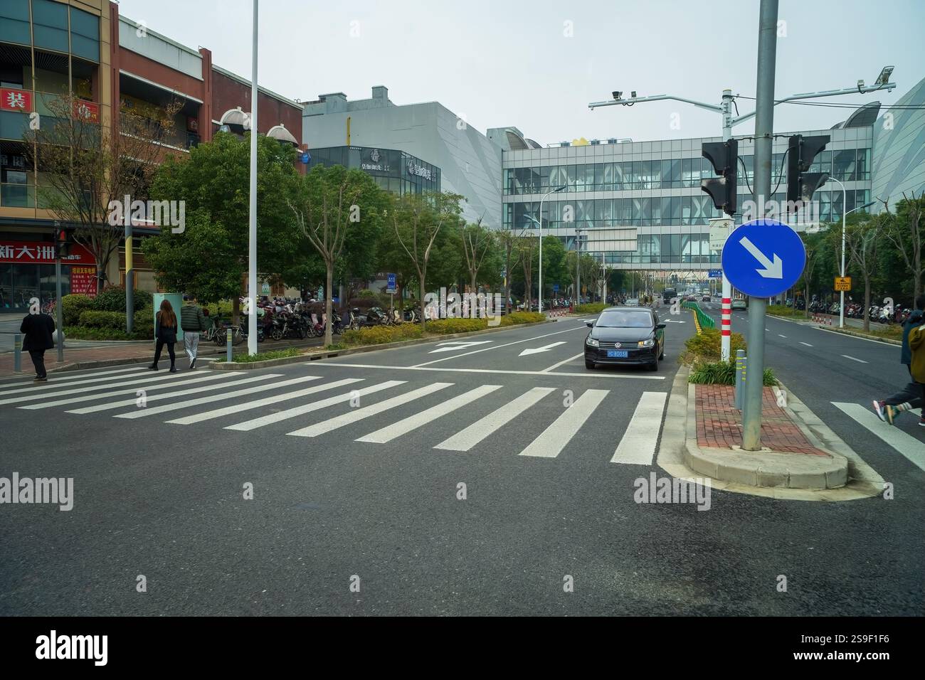 Shanghai, Chine - 7 décembre 2024 piéton traversant la route avec une voiture en attente près du centre SML. Banque D'Images