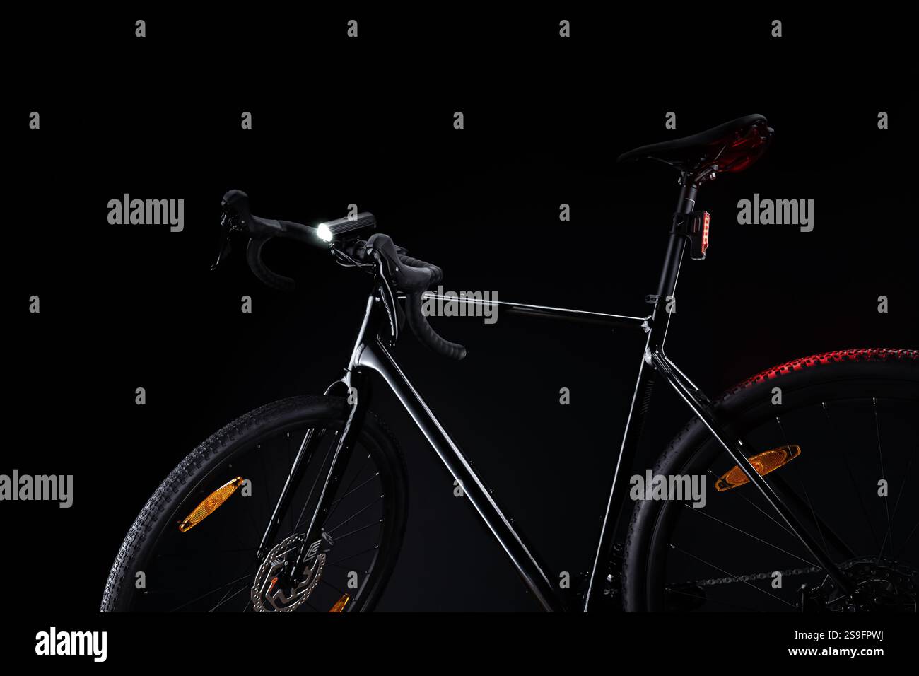 Vélo de gravier noir avec éclairage. Cyclisme de nuit avec phare blanc et clignotant arrière rouge, soulignant la sécurité cycliste et le design élégant contre dar Banque D'Images