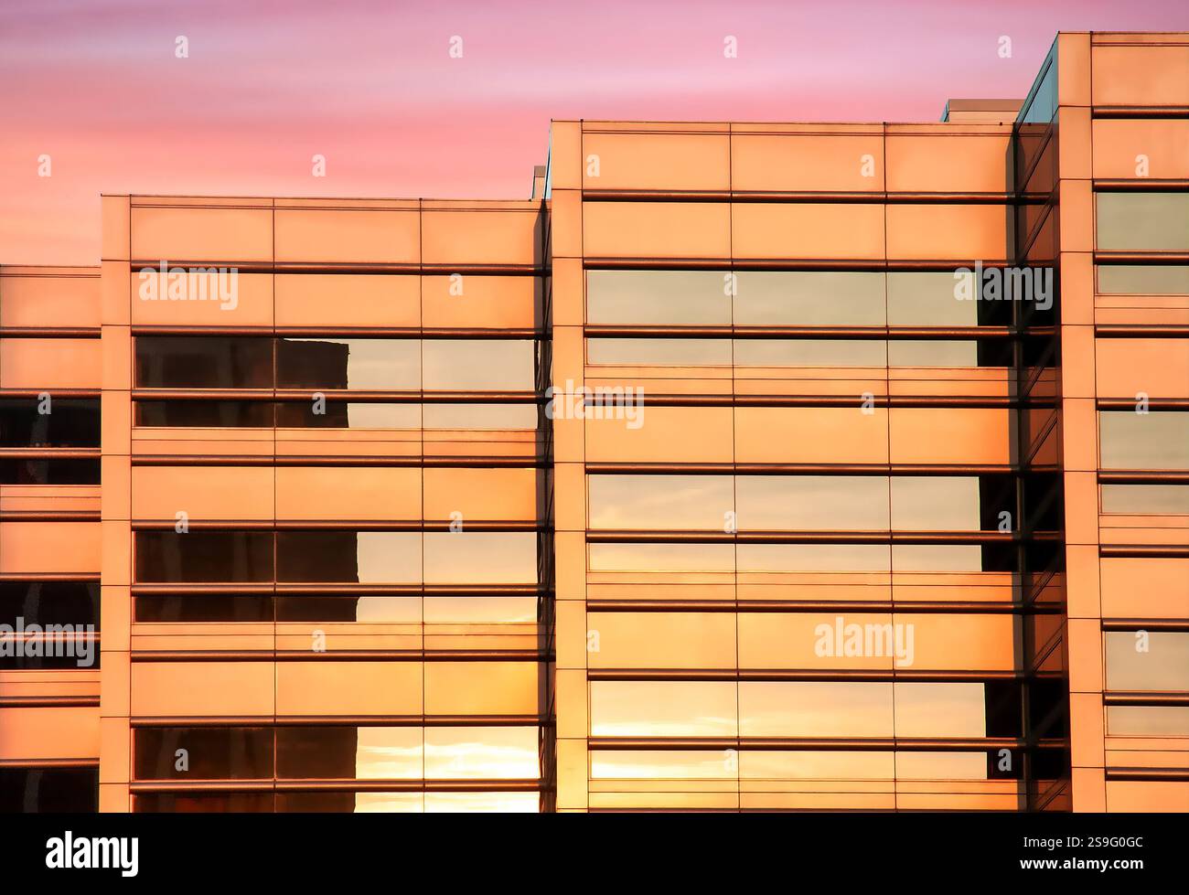 Bâtiment en verre doré reflétant les couleurs du coucher du soleil dans le paysage urbain urbain Banque D'Images