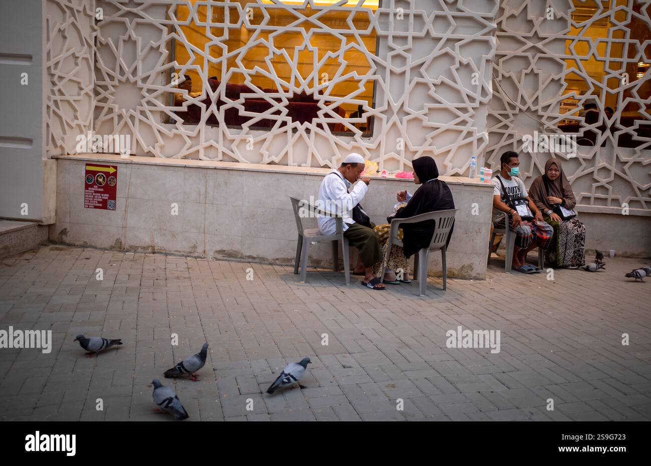 La Mecque, Arabie Saoudite - 10 juin 2024 : pèlerins du Hadj et de l'Oumrah venus d'Indonésie assis devant un hôtel à Makkah, Arabie Saoudite. Hajj 2024. Banque D'Images