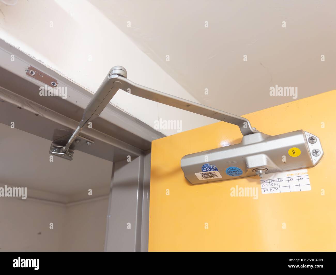 Mécanisme de fermeture de porte fixant une porte orange dans un cadre intérieur Banque D'Images