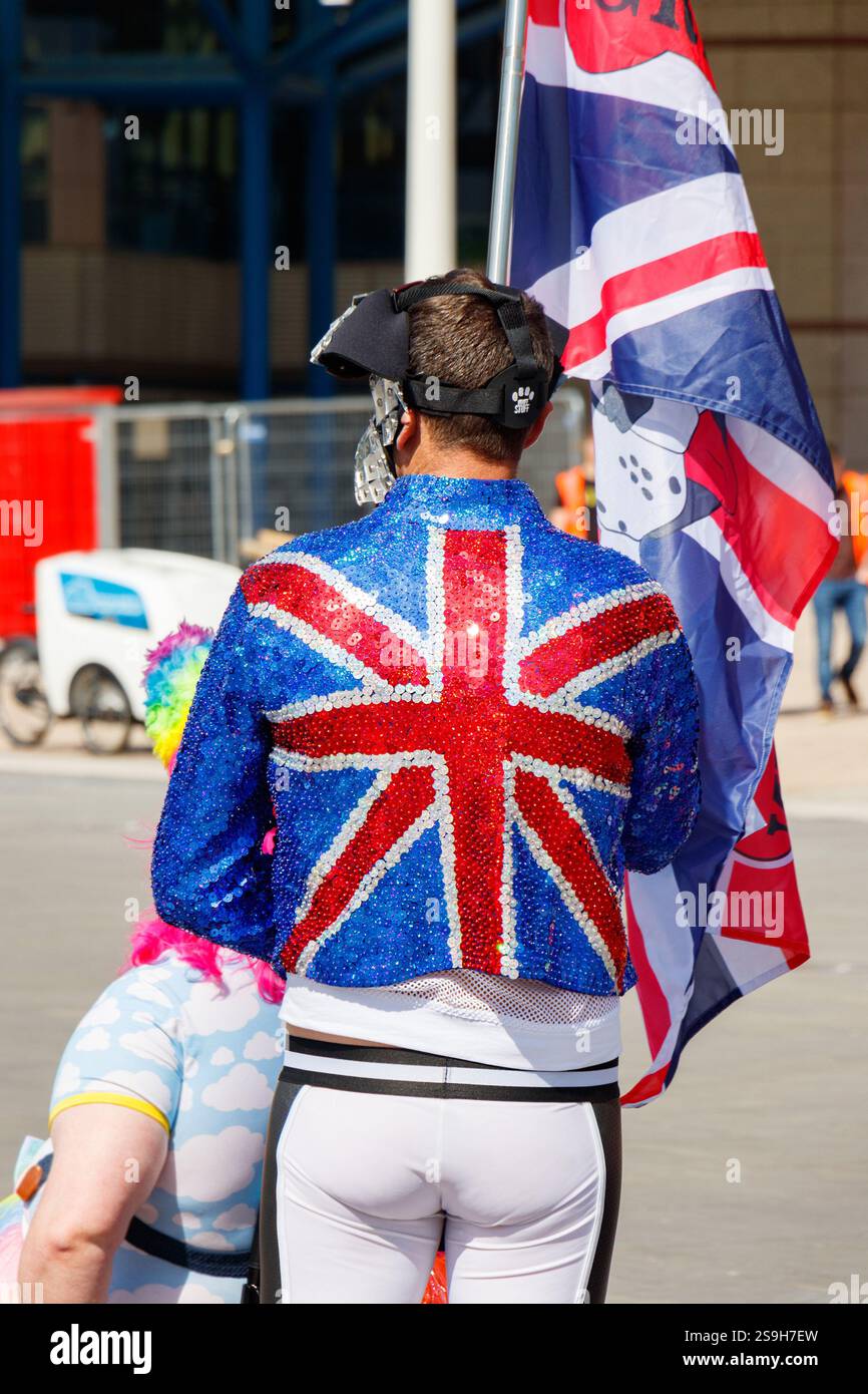 Une personne célébrant la fierté dans une veste union Jack recouverte de paillettes éclatantes et un drapeau tenu haut sur birmingham Pride uk Banque D'Images