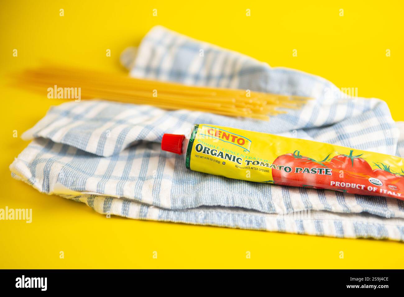 Cento Organic Tomato Paste produit d'Italie. Produit biologique USDA. fond jaune avec des pâtes sèches et un torchon bleu et blanc Banque D'Images
