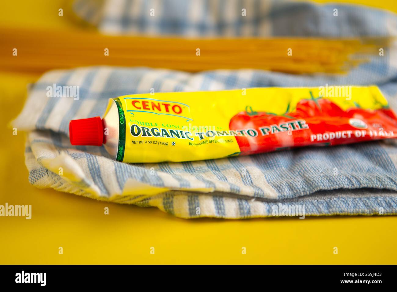 Cento Organic Tomato Paste produit d'Italie. Produit biologique USDA. fond jaune avec des pâtes sèches et un torchon bleu et blanc Banque D'Images
