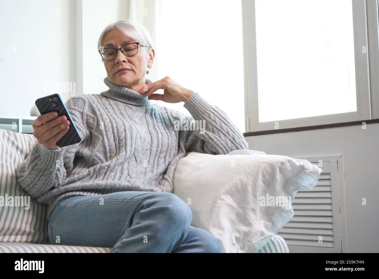 Femme âgée commandant des courses en ligne à l'aide de son smartphone Banque D'Images
