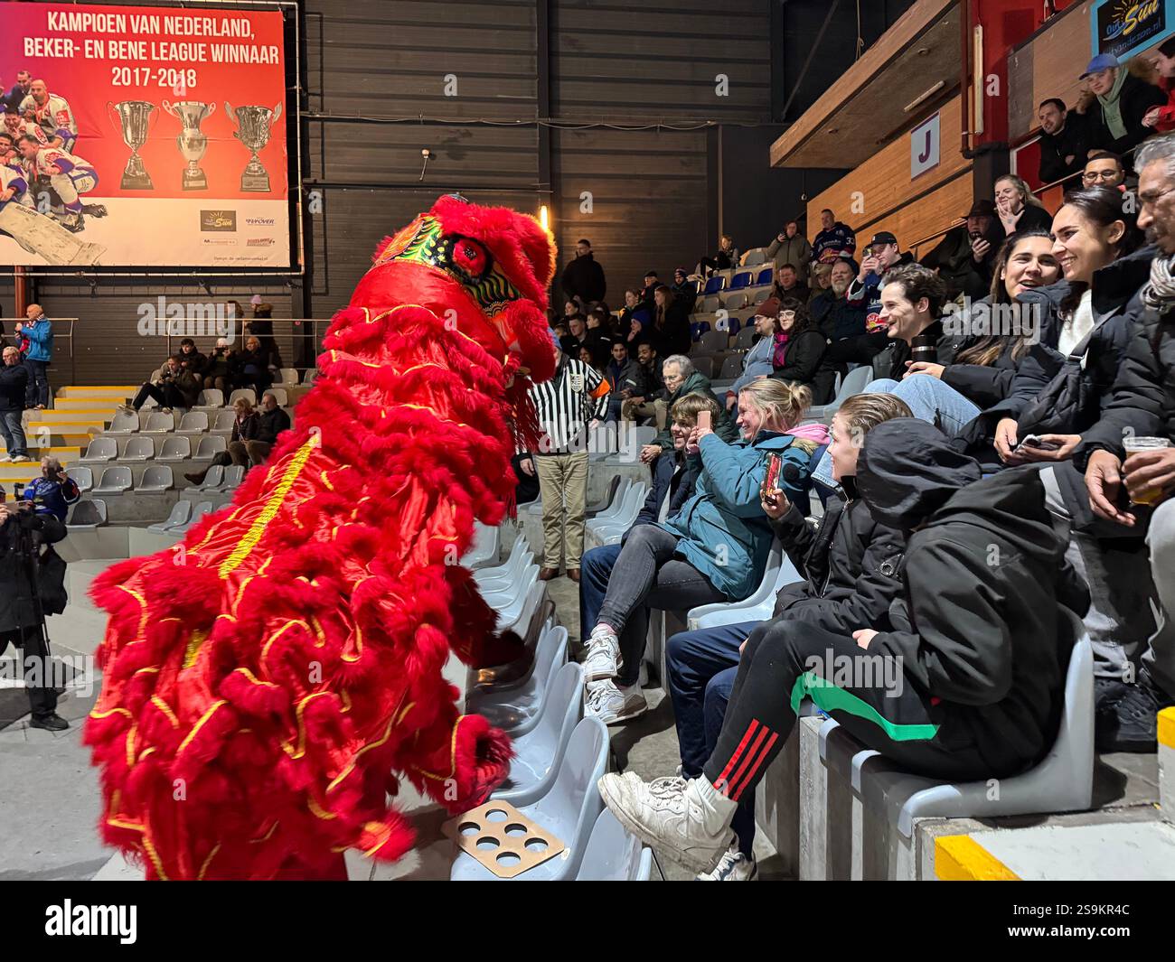 La Haye, pays-Bas. 24 janvier 2025. Les spectateurs interagissent avec des artistes de danse du lion depuis les tribunes de la patinoire de hockey sur glace du de Uithof Sports Center à la Haye, aux pays-Bas, le 24 janvier 2025. Le choc retentissant des gongs et des tambours a fait écho à l'arène de hockey sur glace de la Haye vendredi soir alors qu'une danse du lion animée a captivé les spectateurs néerlandais lors de la célébration du « Happy Spring Festival ». POUR ALLER AVEC 'la danse du lion déclenche des échanges culturels dans l'arène de hockey sur glace néerlandaise' crédit : Sun Jingjing/Xinhua/Alamy Live News Banque D'Images